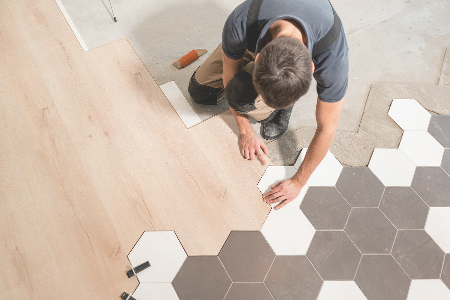 male-worker-installing-new-wooden-laminate-flooring-honeycomb-kitchen-renovation