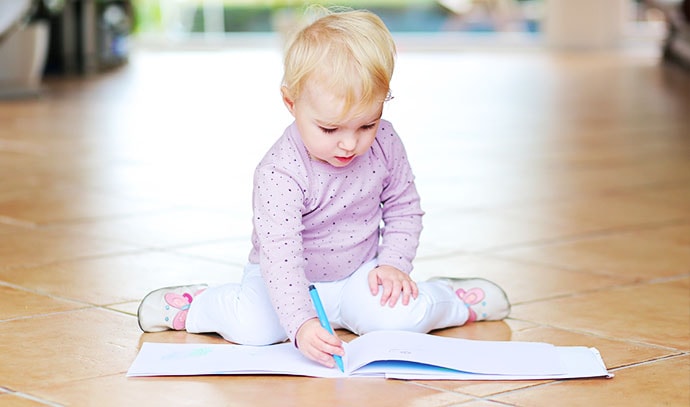 kid-baby-sitting-on-floor-writing-playing