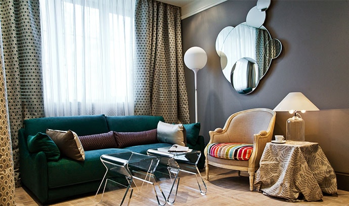 round-mirror-on-wall-green-couch-dotted-curtains-beige-sidetable-living-room