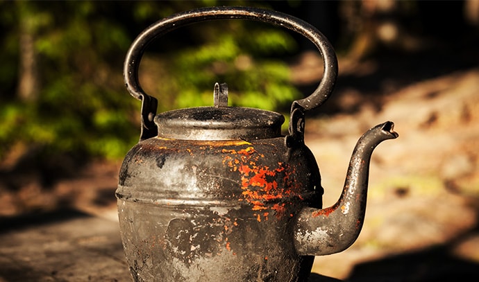 old-rusty-kettle-in-wooden-bench-outdoors