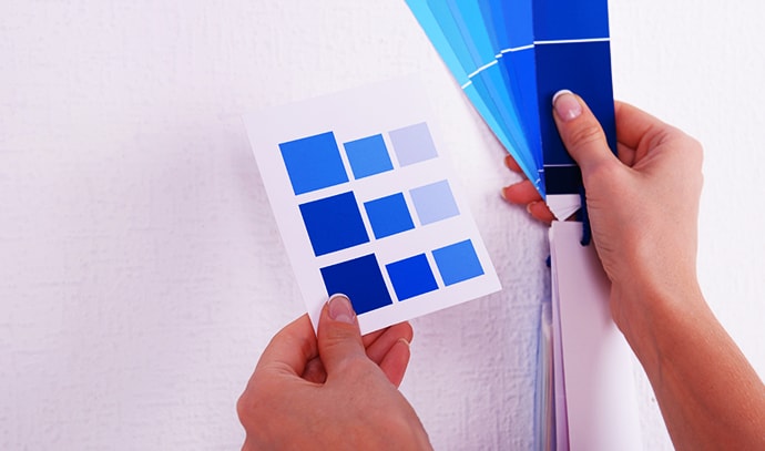 woman-choosing-color-wall-swatches-blue-room