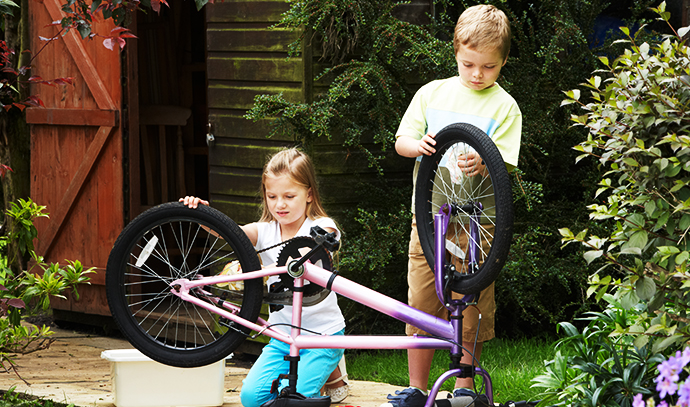 two-boy-girl-children-cleaning-bike-together-backyard