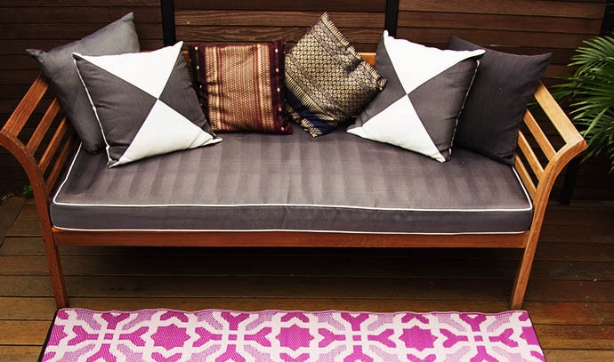 purple-rug-wooden-couch-loveseat-neutral-pillows