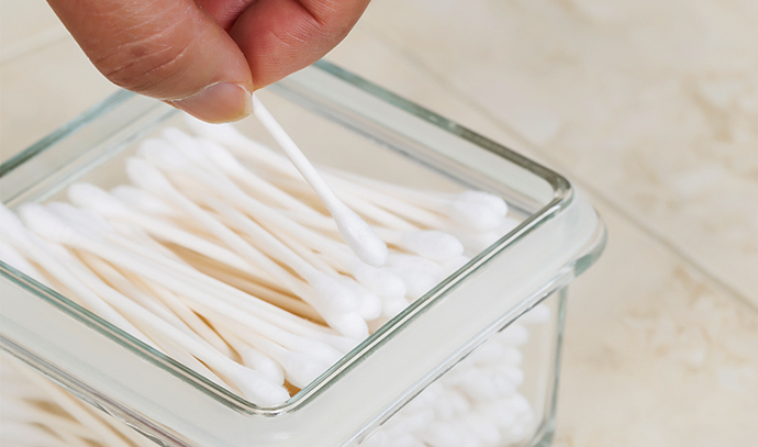 closeup-horizontal-photo-female-hand-picking-up-single-cotton-swab-out-glass-container-white-tile-background