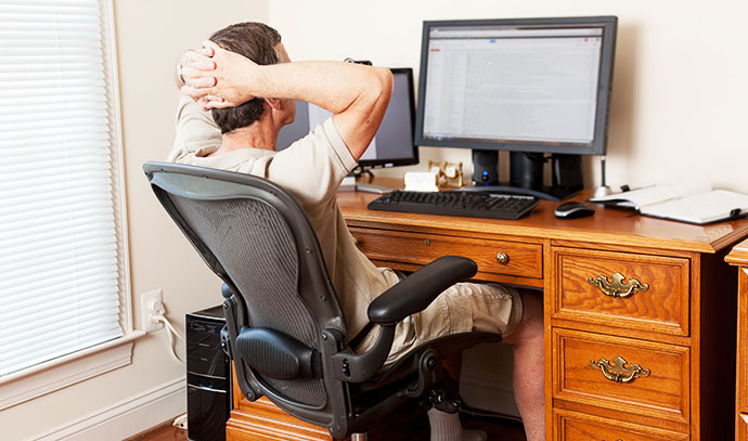 senior-caucasian-man-working-home-shorts-desk-two-monitors