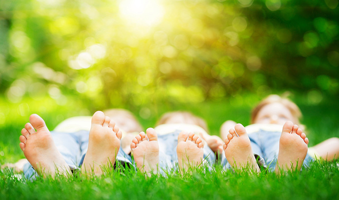 kids-triplets-laying-outside-green-lawn-small-feet