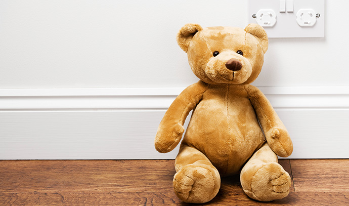 teddy-bear-toy-near-power-outlet-wooden-floor