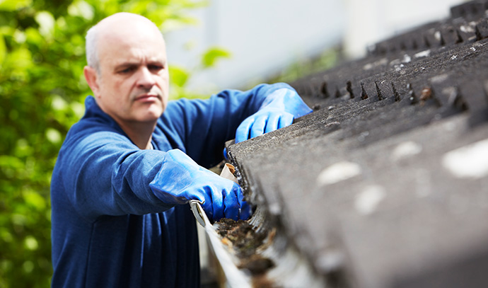 man-clearing-leaves-guttering-house