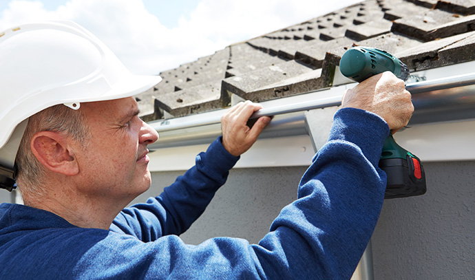 workman-replacing-guttering-exterior-house