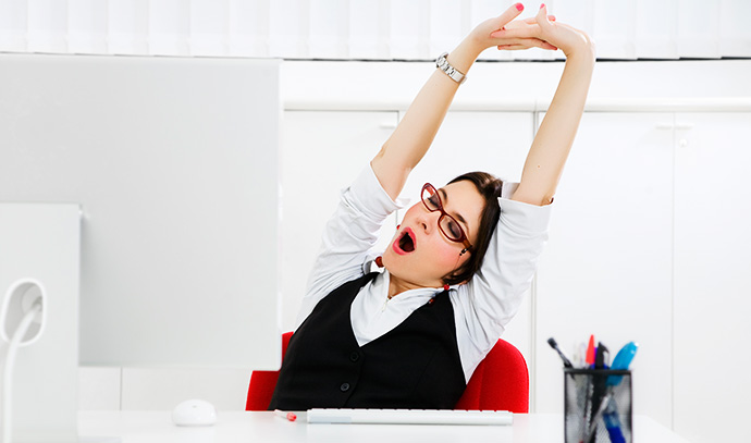 young-businesswoman-sitting-desk-yawning