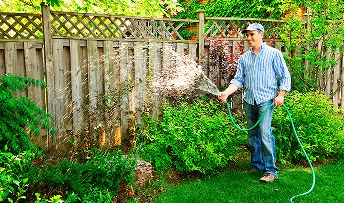 man-watering-garden-backyard-hose