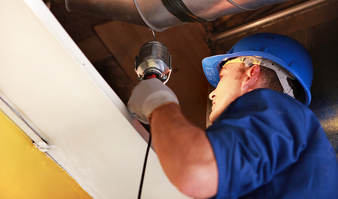 man-worker-blue-uniform-hard-hat-examining-attic-repair-vent