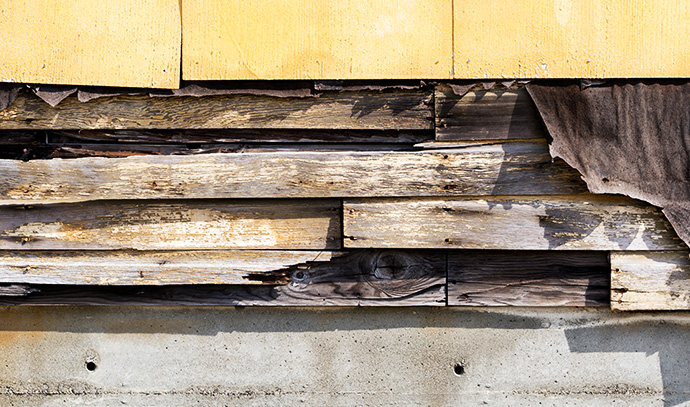 asbestos-siding-falling-apart-exposed-wood-felt-underneath-old