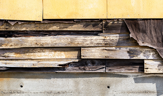 asbestos-siding-falling-apart-exposed-wood-felt-underneath-old