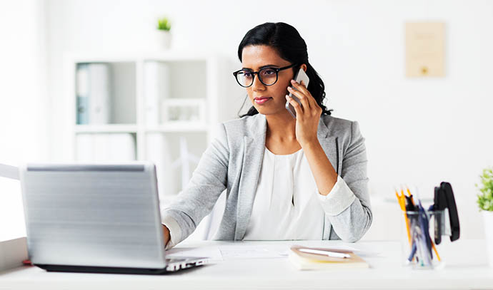 happy-businesswoman-laptop-computer-calling-smartphone-office