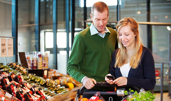 happy-couple-buying-groceries-looking-grocery-list-phone