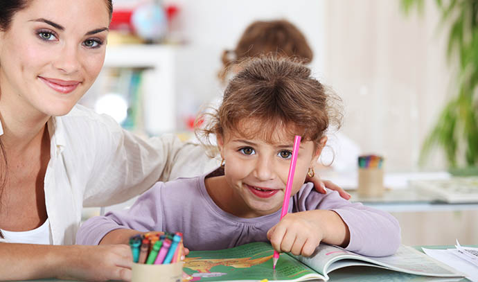 little-girl-preschool-drawing-coloring-teacher-guiding