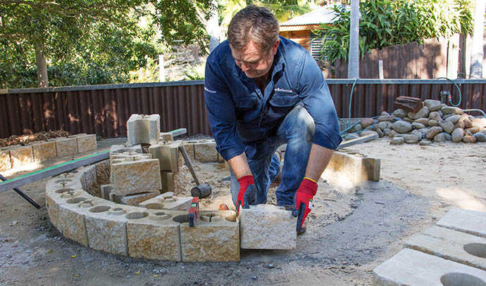 adbrimasonry-man-layering-first-course-blocks-fire-pit